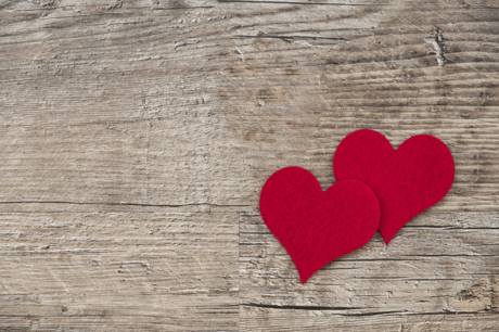 Two cloth hearts pinned against a wooden wall.