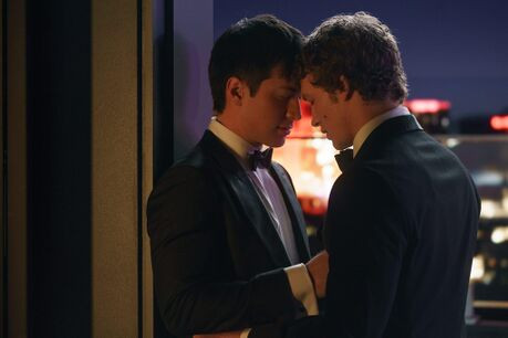 Ilya Rozanov and Shane Hollander from Heated Rivalry, wearing suits and standing forehead to forehead.